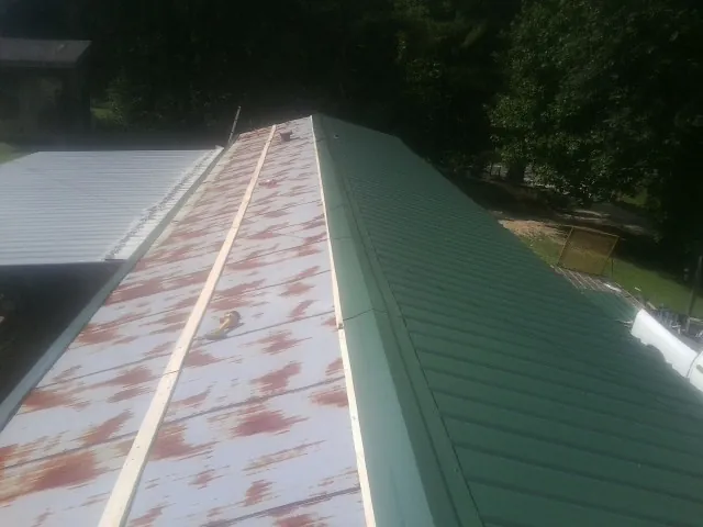 Old rusted panels beside newly installed green metal roofing — Wind Damage Roof Repair by Roofing Brothers in Sneedville