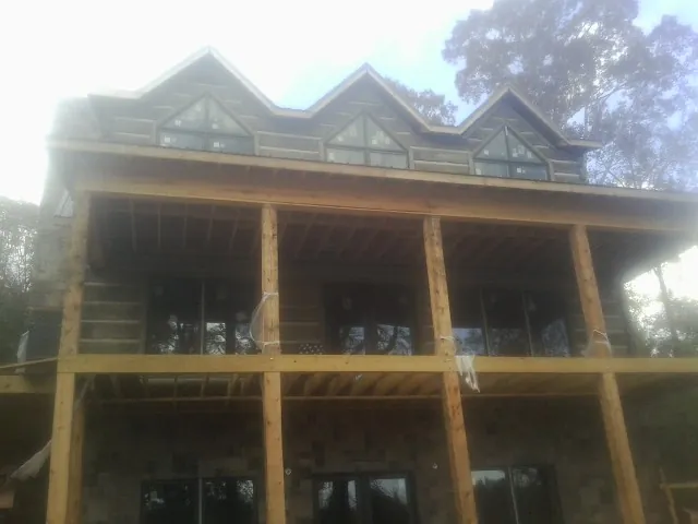 Dormers and porch framing on a large log home under construction — Roof Coating work by our crew in Sneedville