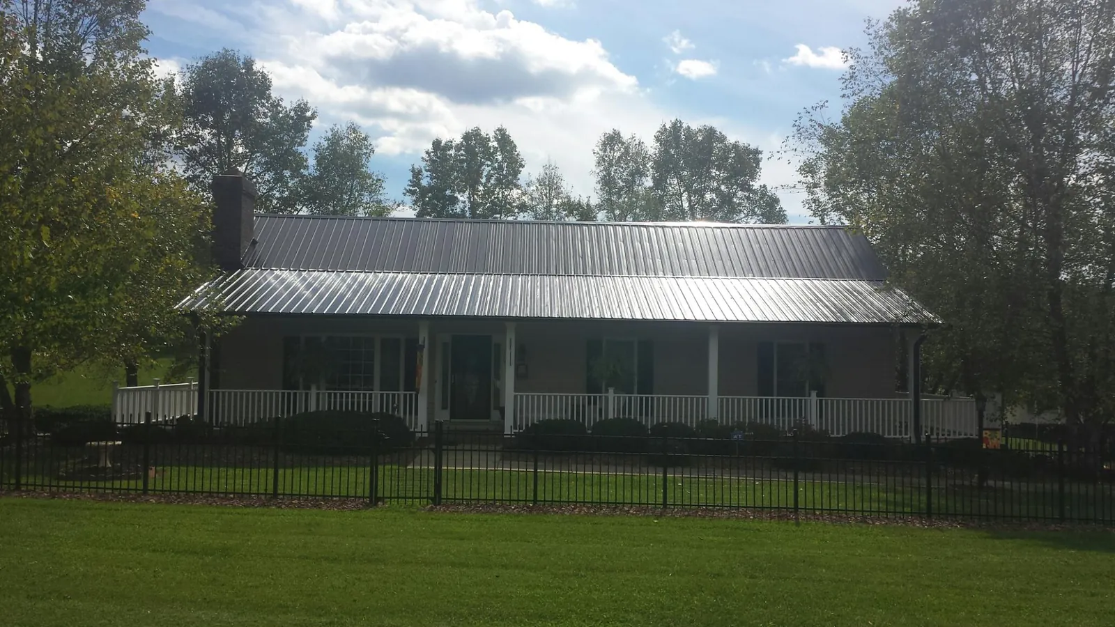 Gray metal roof on a brick ranch with a full width front porch — Gutter Guard Installation work by our crew in Sneedville