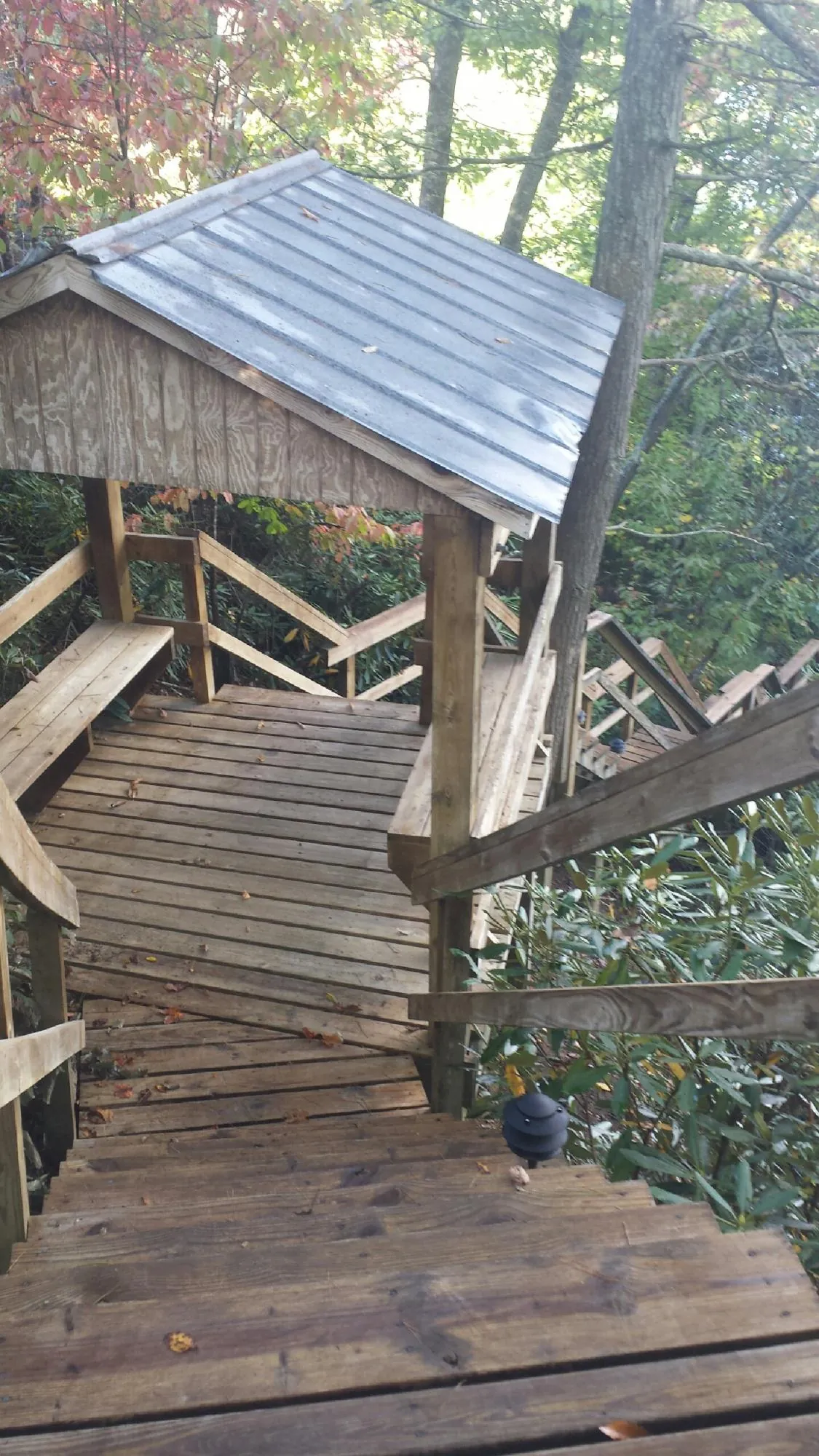 Metal roofed shelter over wooden steps on a wooded walkway — Skylight Repair & Installation work by our crew in Sneedville
