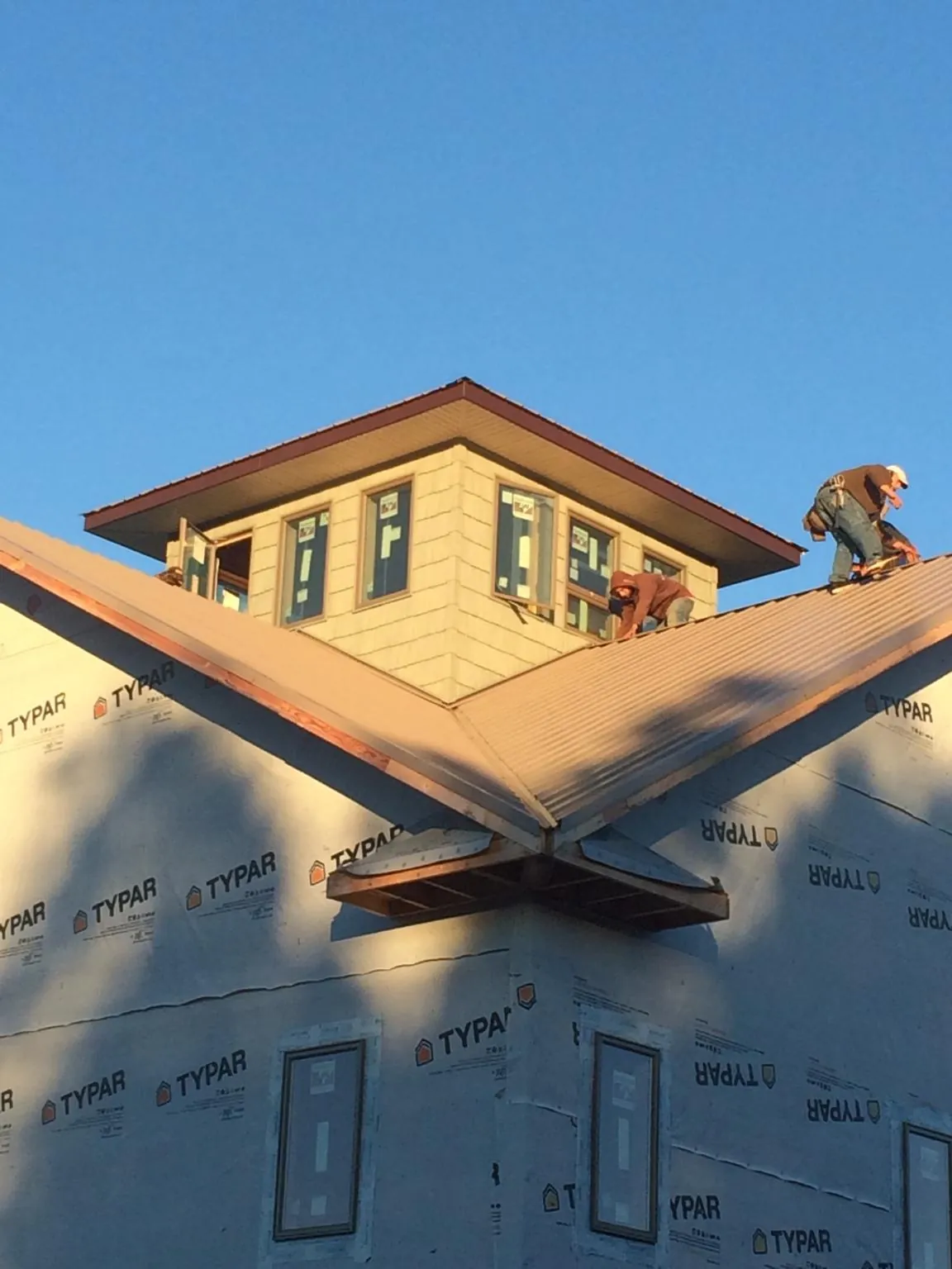 Roofers working around a rooftop cupola on a new metal roof at sunset — Roof Waterproofing in Sneedville by Roofing Brothers